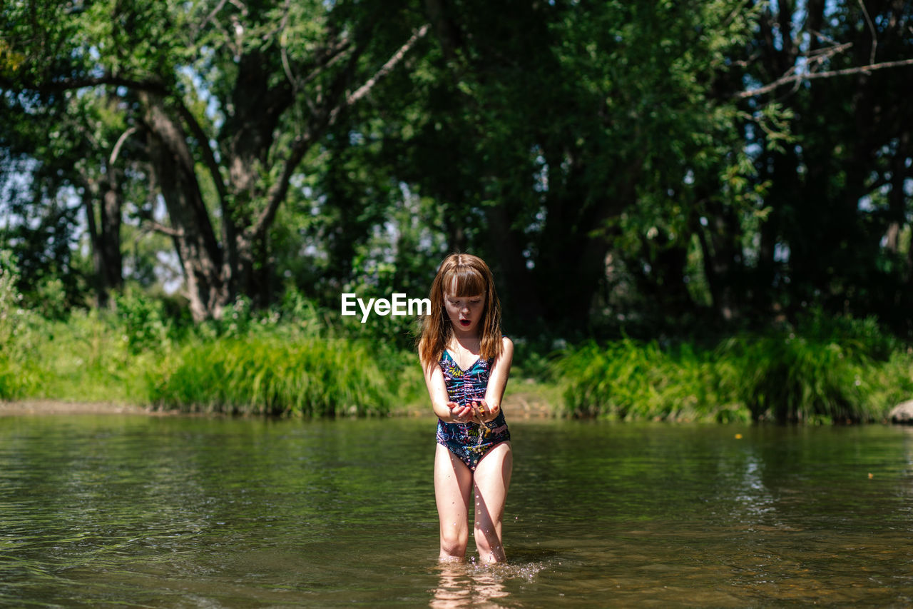 Excited young girl playing in a creek on a sunny day