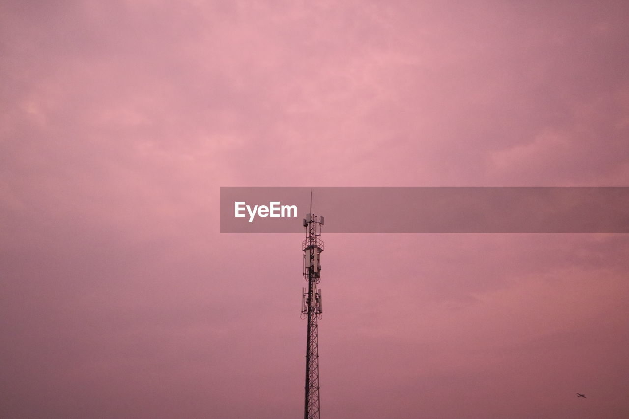 Low angle view of electricity pylon against sky during sunset