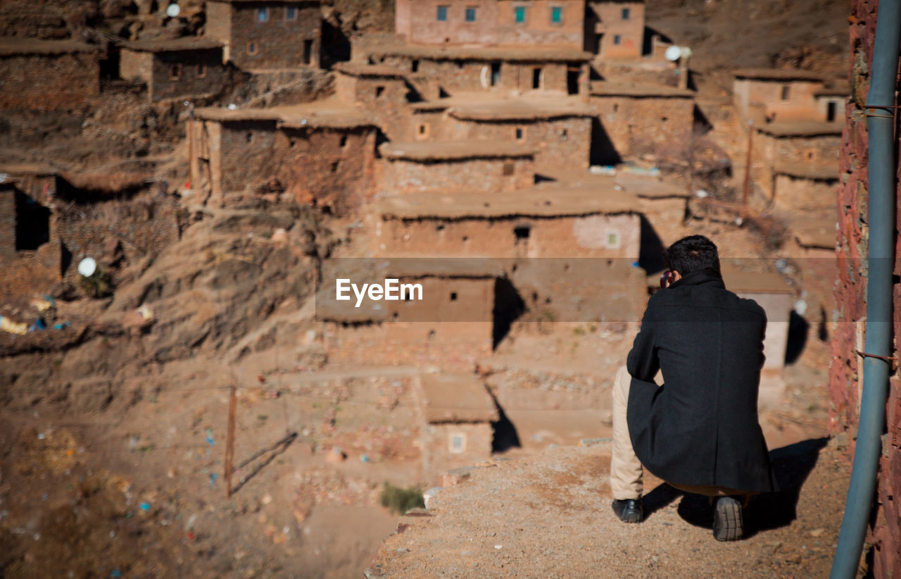 Rear view of young man crouching on old ruin