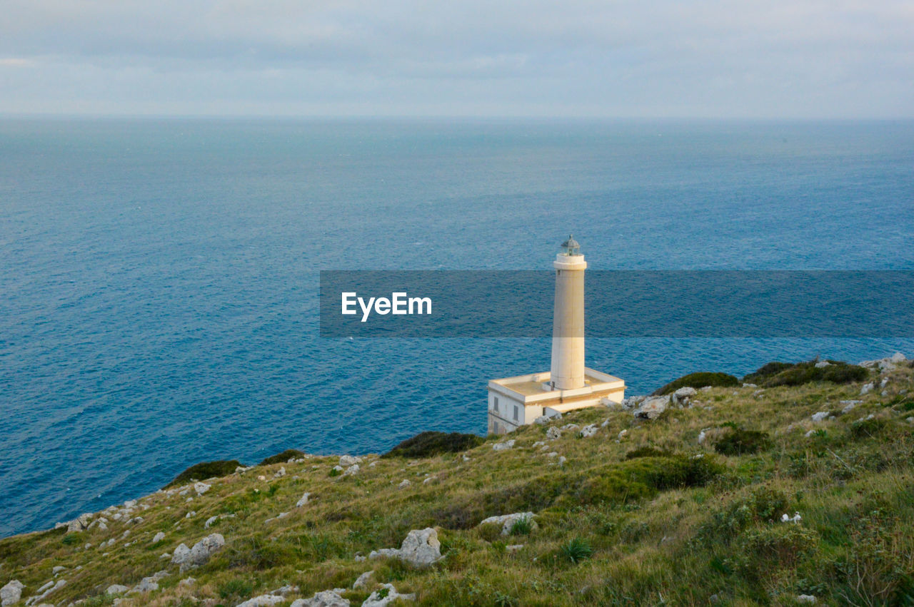 tower, sea, lighthouse, water, guidance, coast, architecture, built structure, building exterior, security, sky, ocean, nature, protection, building, scenics - nature, no people, land, horizon, horizon over water, beach, day, beauty in nature, travel destinations, shore, coastline, cliff, travel, outdoors, history, high angle view, non-urban scene, tranquility, hill, the past, promontory, plant, cloud, tranquil scene, bay, grass, environment, island, tourism, blue, cove