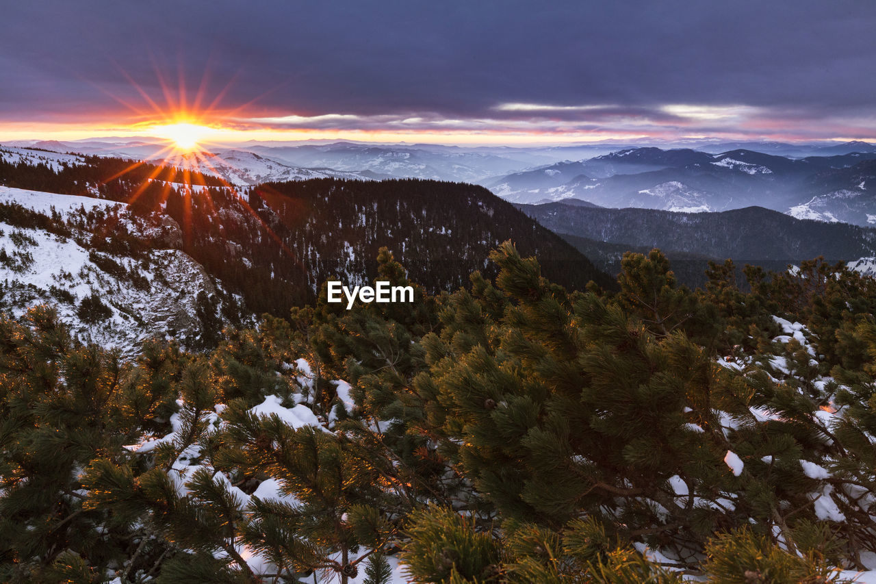 Scenic view of snowcapped mountains against sky at sunset