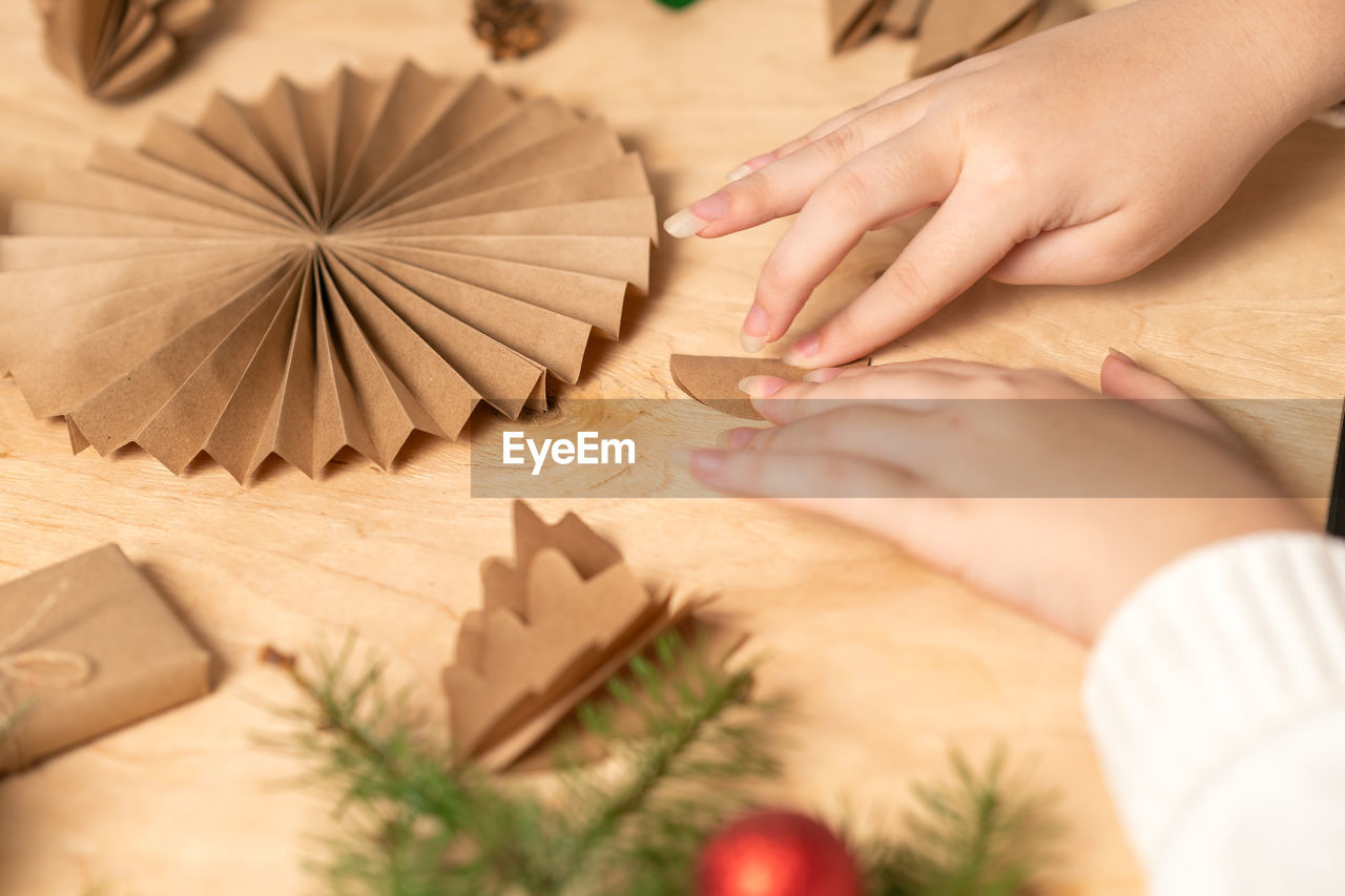 Girl makes christmas tree decorations out of paper with her own hands. step 3