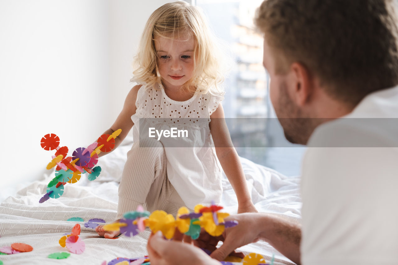 Side view of father and daughter playing with construction 