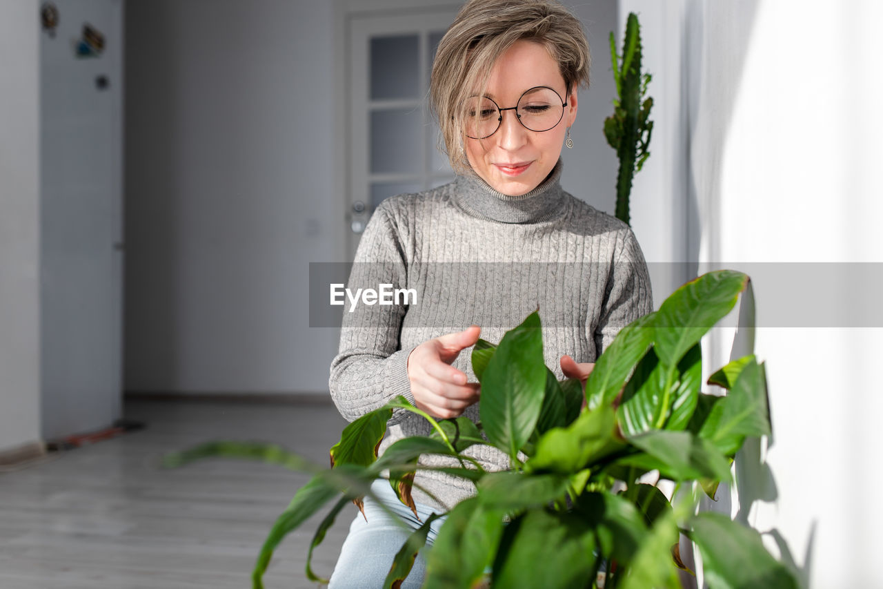 Woman touching plant at home