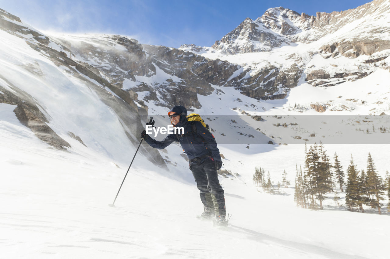 Hiker battles wind above black lake, rocky mountain national park