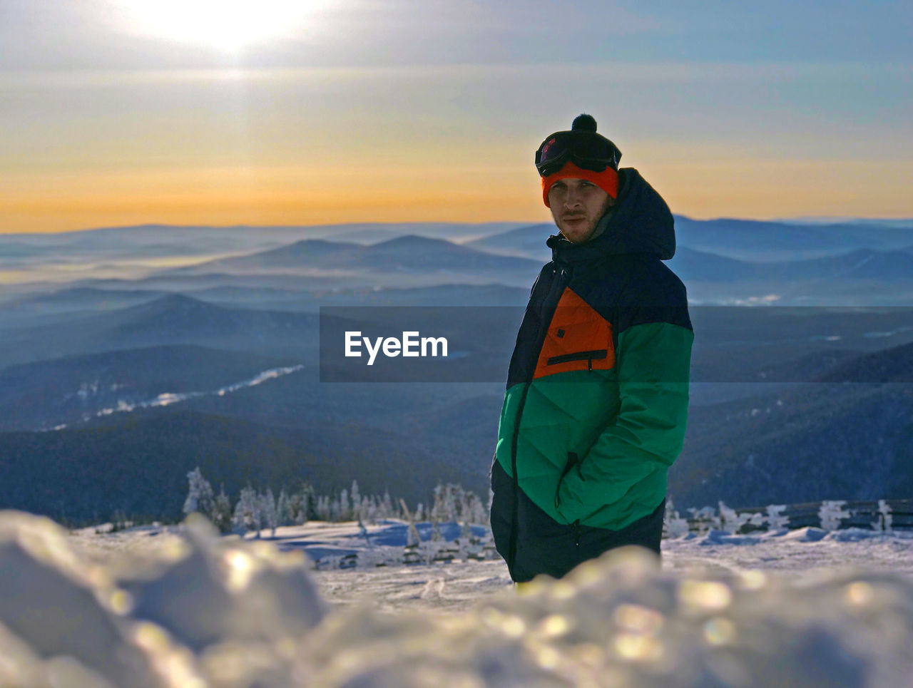 Portrait of man standing against snowcapped mountains during sunset