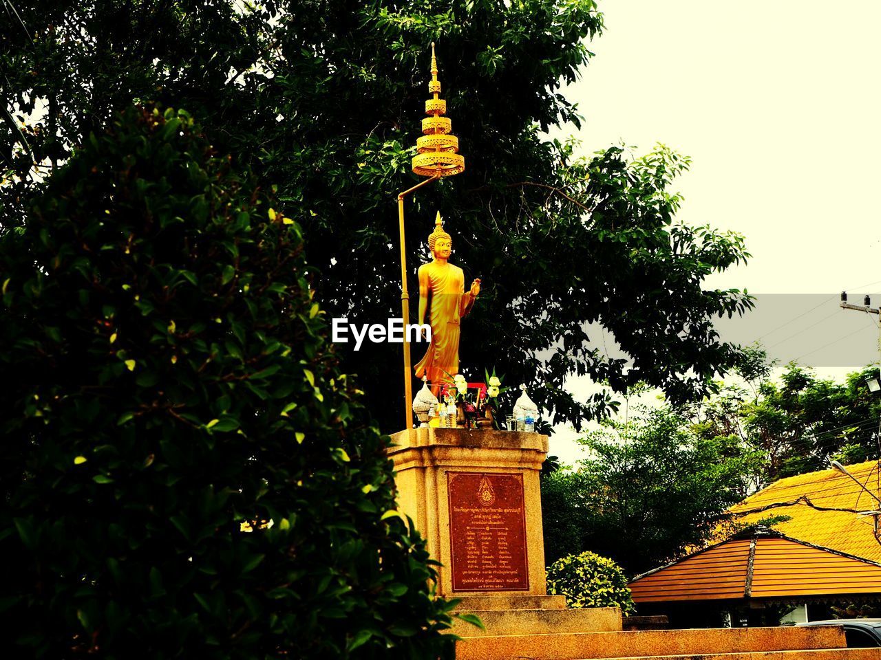 LOW ANGLE VIEW OF STATUE AGAINST BUILDING AND TREES