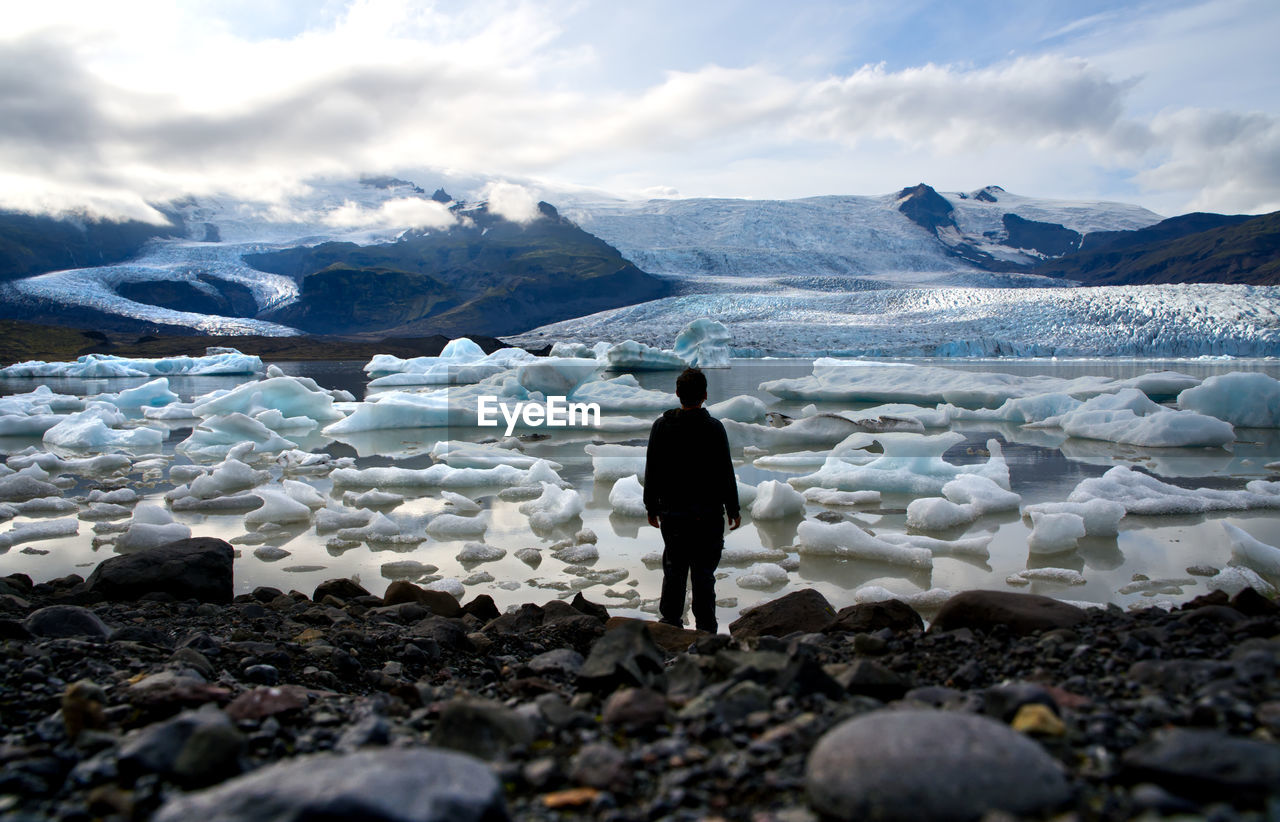 Rear view of man standing on snowcapped mountain