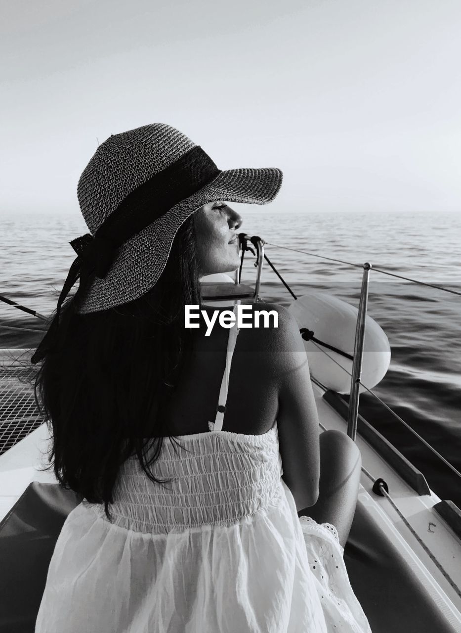 Rear view of woman sitting on boat against sea