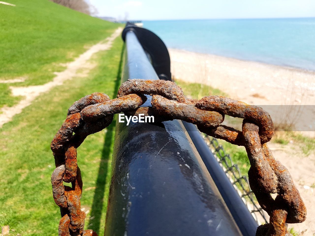 CLOSE-UP OF RUSTY CHAIN ON SHORE