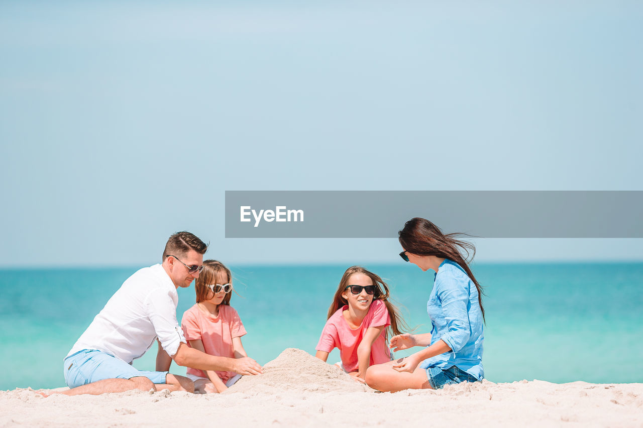 People on beach against clear sky