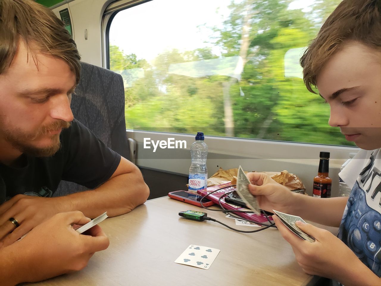 Father and son playing cards in a train