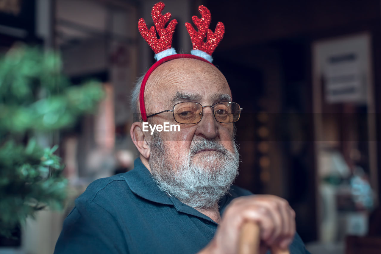 Portrait of depressed elderly man with reindeer ears