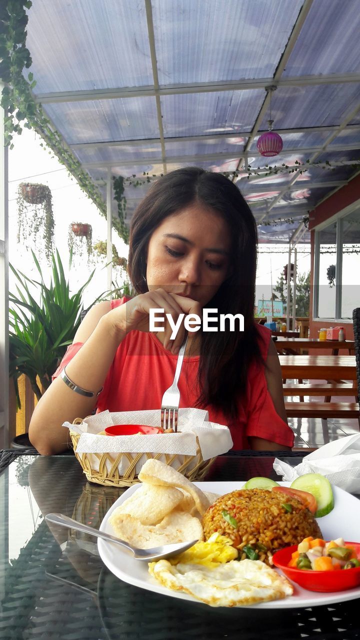 PORTRAIT OF WOMAN SITTING IN RESTAURANT TABLE