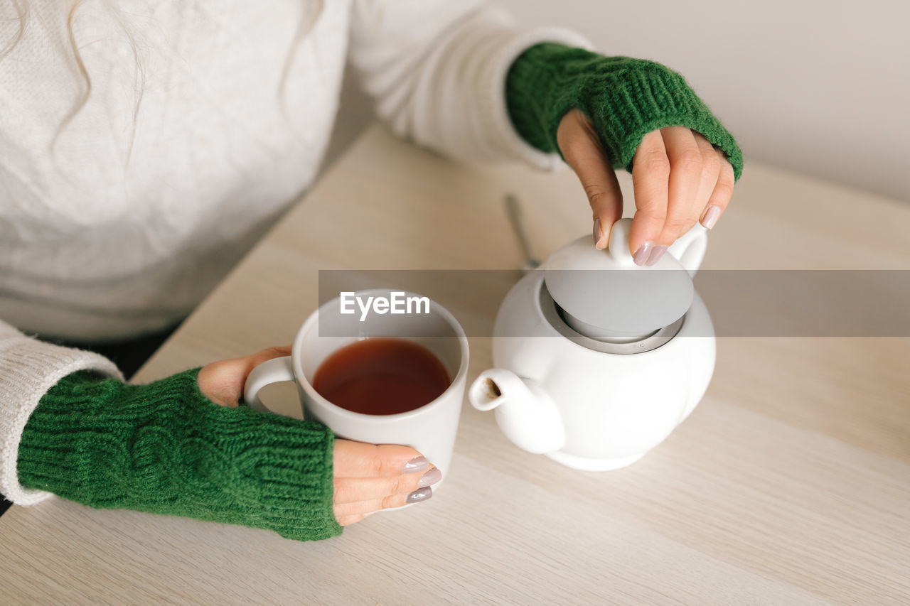 High angle view of hand holding tea cup on table