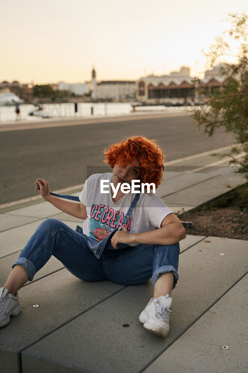 Young alternative redhead girl posing at sunset in a overall