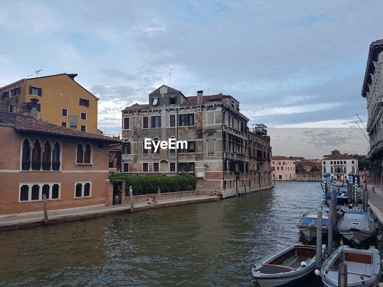 Canal amidst buildings in city against sky