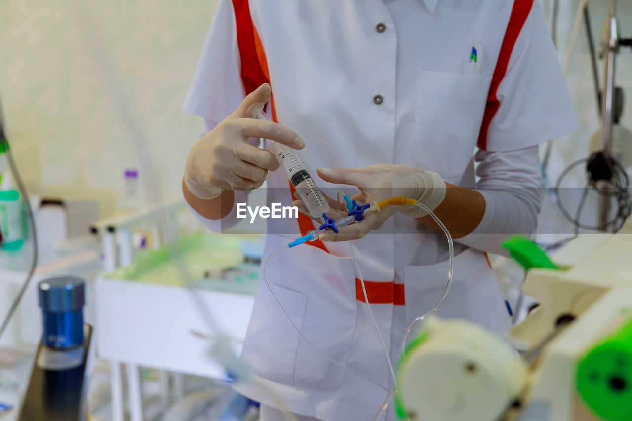 Midsection of doctor holding syringe in hospital