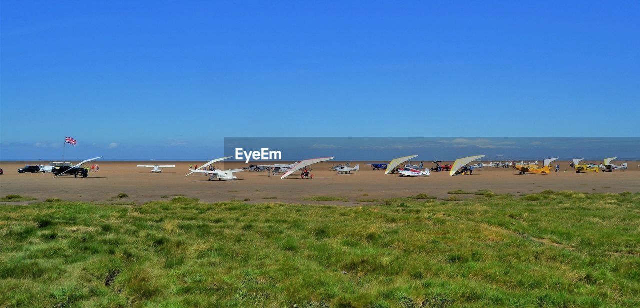 Multiple light aircraft on a beach against blue sky