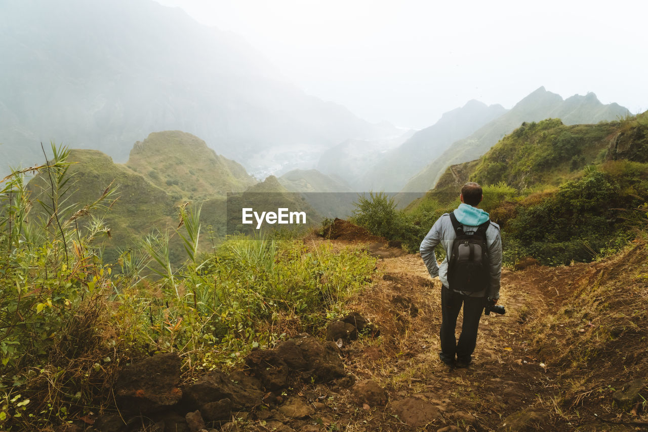 Man standing on land against mountains