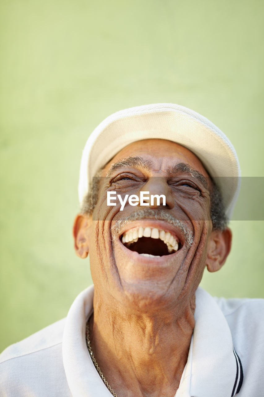 Senior man laughing against wall