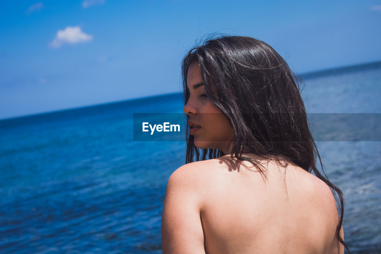 Portrait of woman standing against blue sea