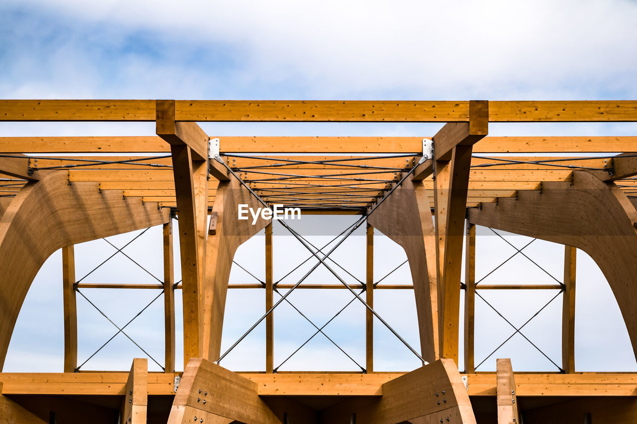 Detail of a modern wooden architecture in glued laminated timber on a blue cloudy sky