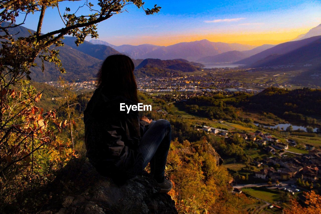 Woman sitting on rock against mountains