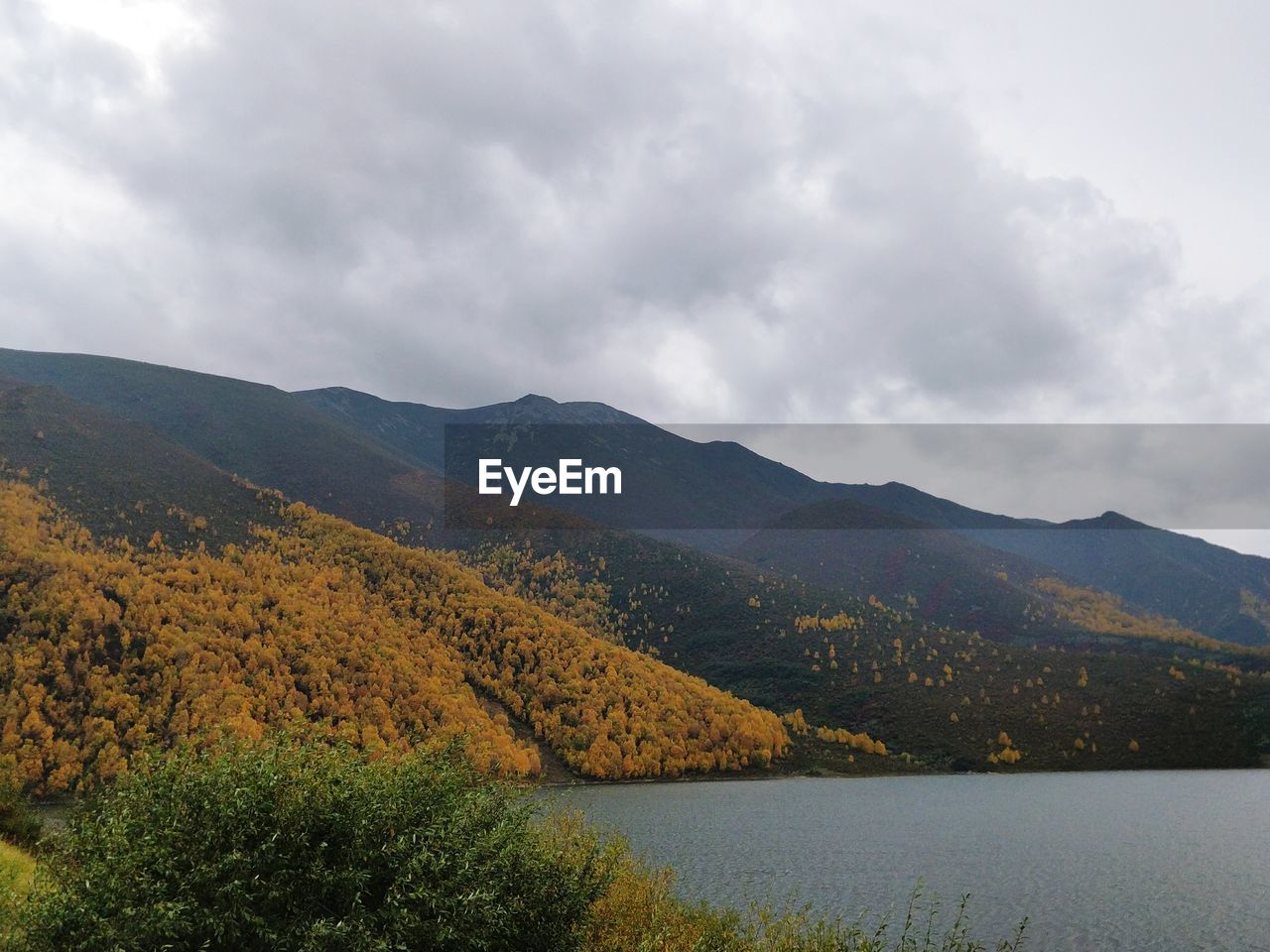 SCENIC VIEW OF MOUNTAINS AND LAKE AGAINST CLOUDY SKY