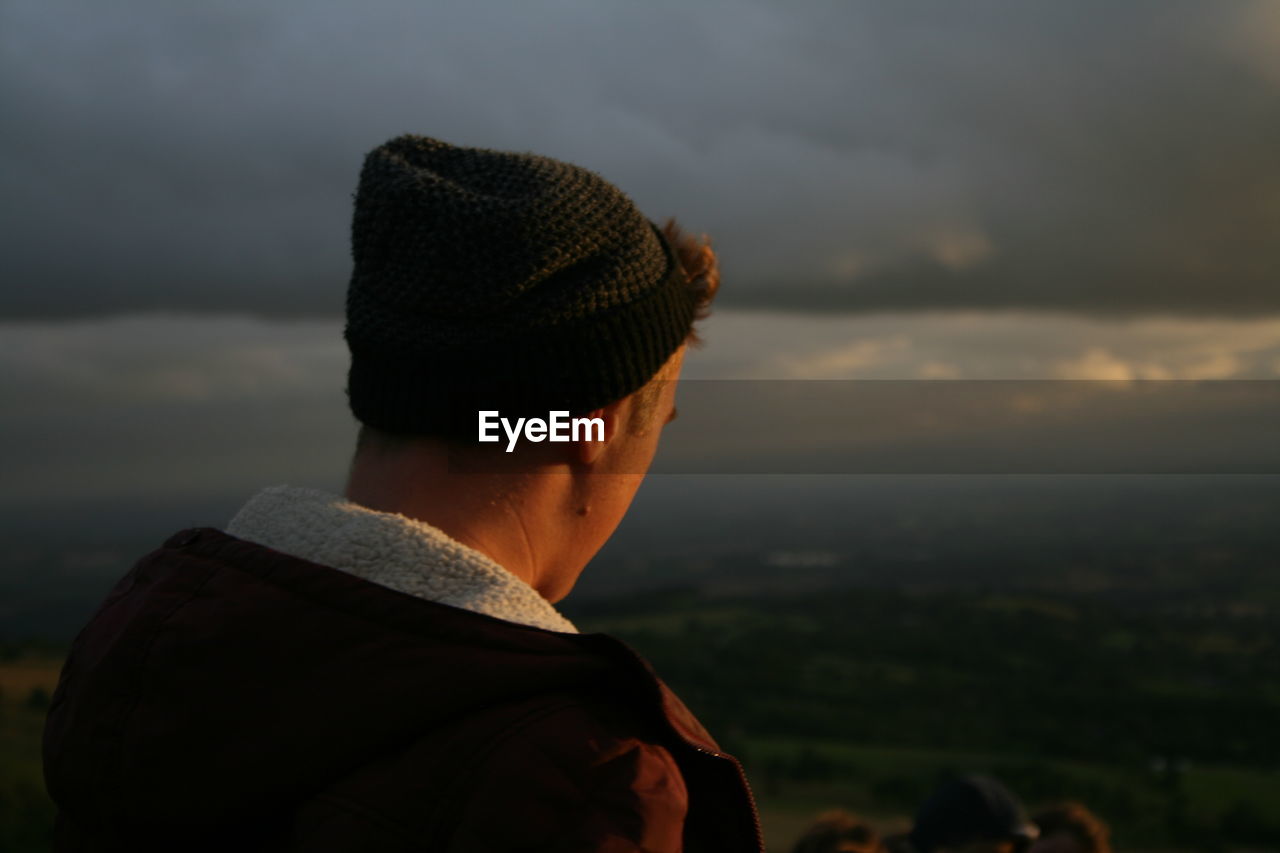 Rear view of teenage boy against cloudy sky