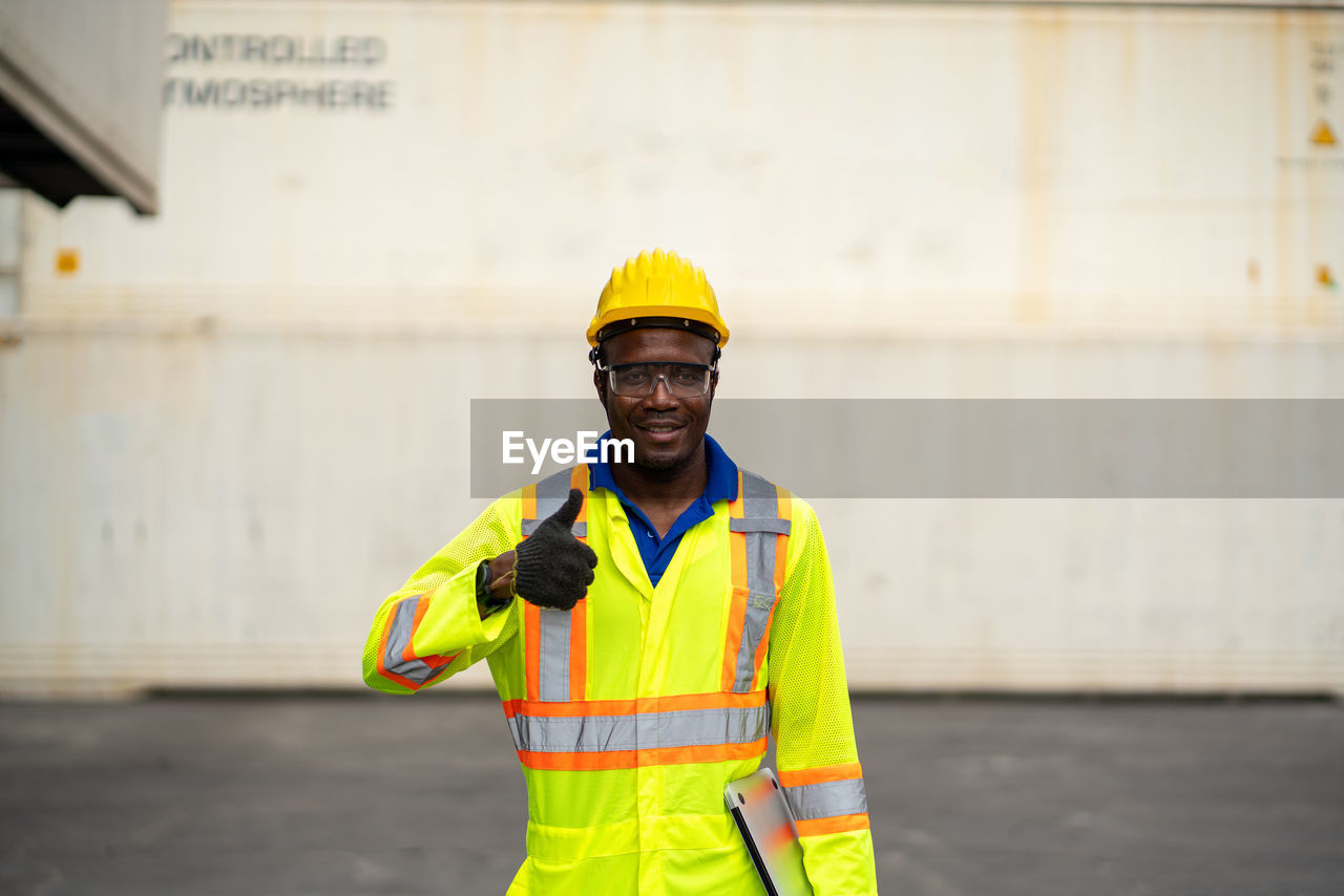Portrait of worker showing thumbs up while standing at dock