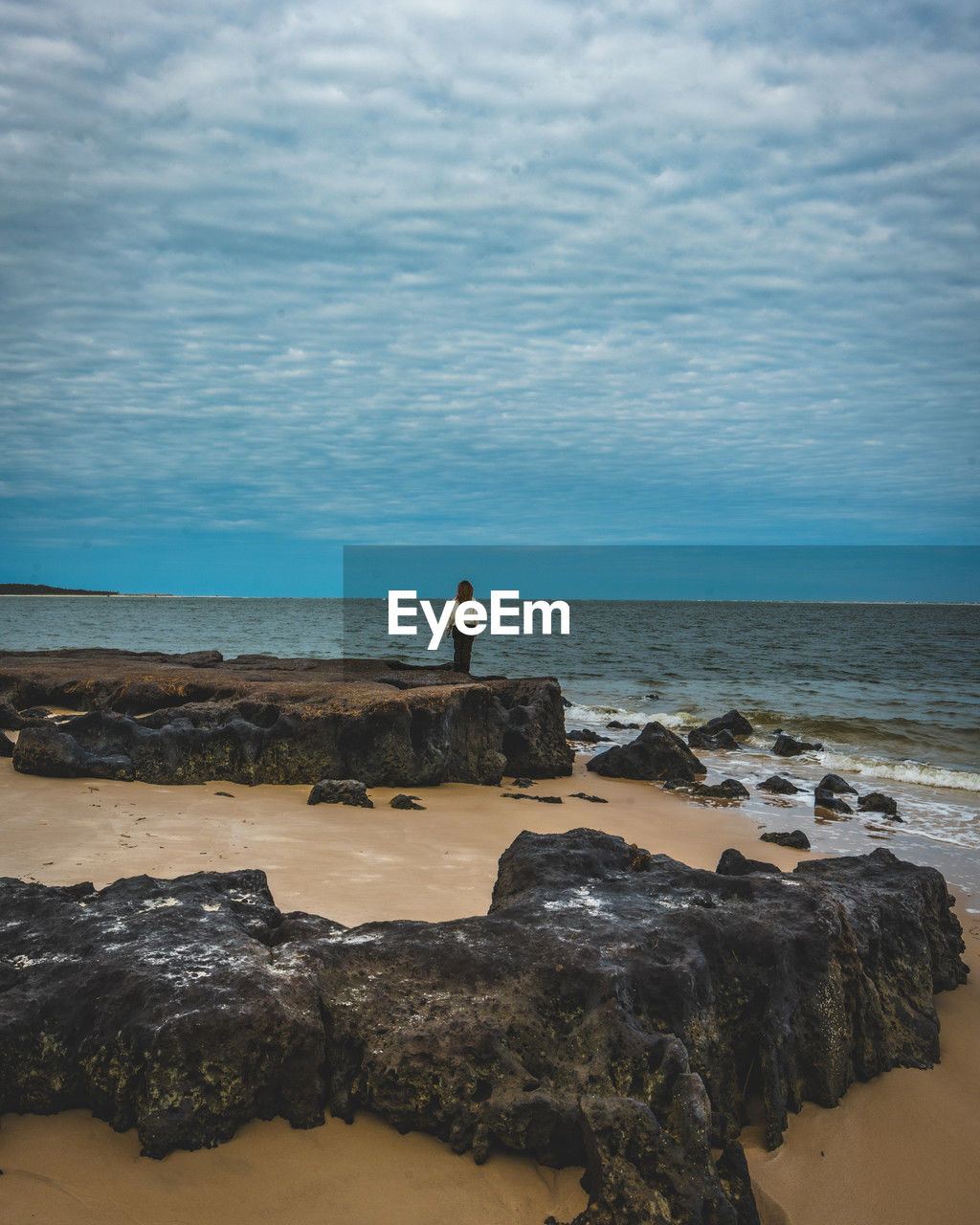 sea, water, land, beach, ocean, sky, shore, horizon, coast, horizon over water, beauty in nature, rock, wave, body of water, scenics - nature, nature, one person, sand, cloud, tranquility, bay, tower, full length, holiday, standing, tranquil scene, wind wave, vacation, trip, outdoors, adult, cliff, travel destinations, coastline, leisure activity, men, day, idyllic, cove, travel, lifestyles, non-urban scene, terrain, motion, lighthouse