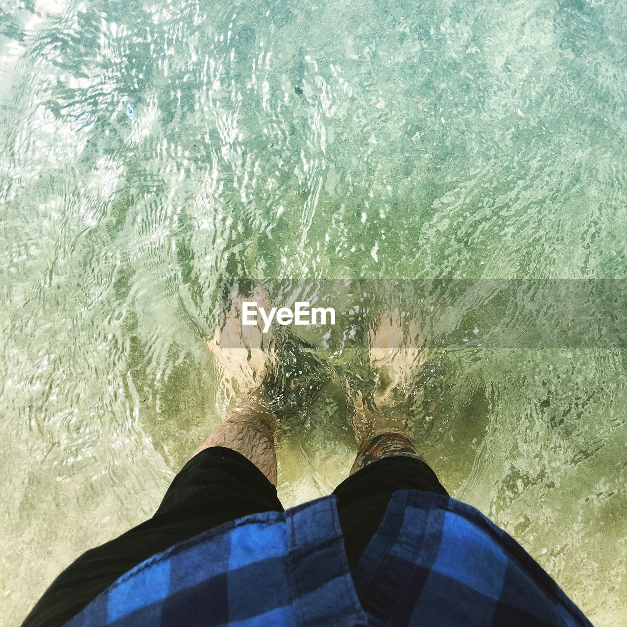 Low section of man with ankle deep in sea