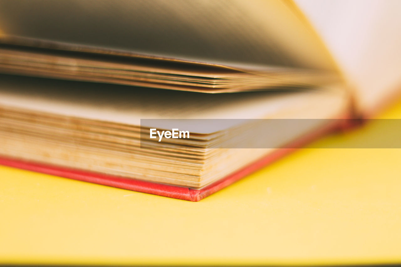 Antique book with worn out pages with red spine on yellow background, concept of learning 