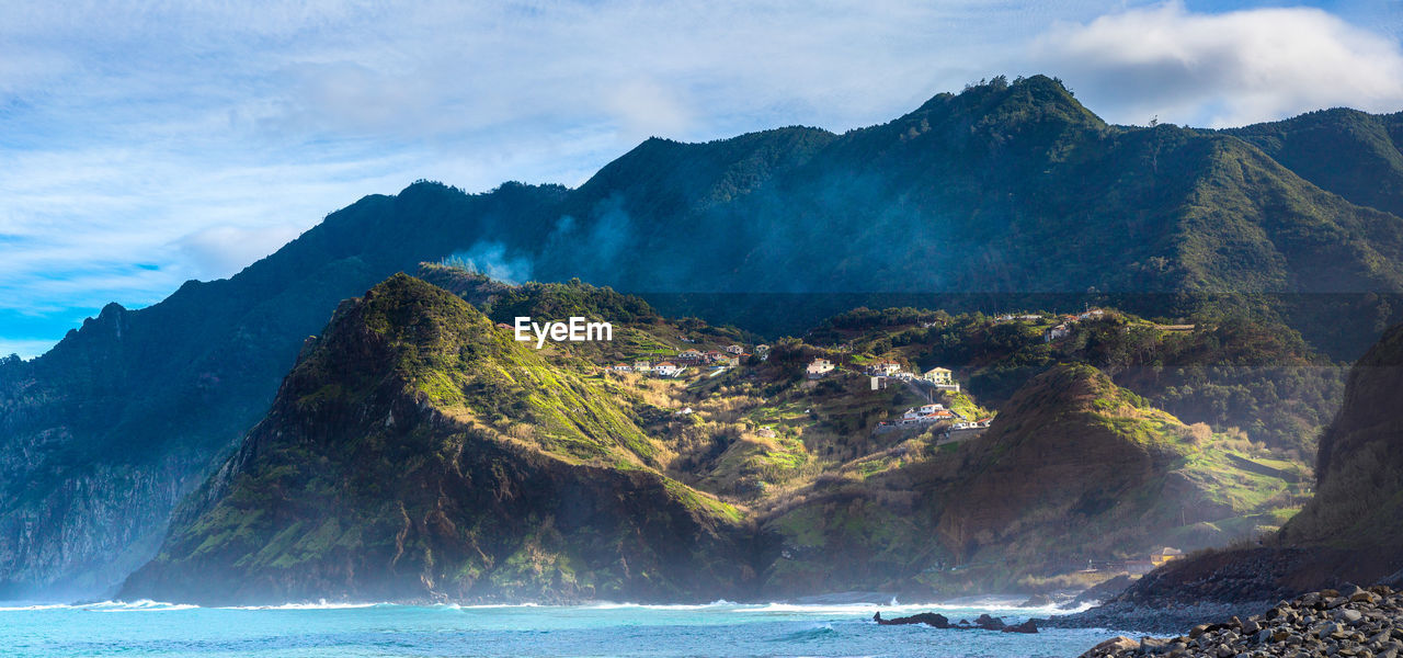 Scenic view of sea and mountains against sky