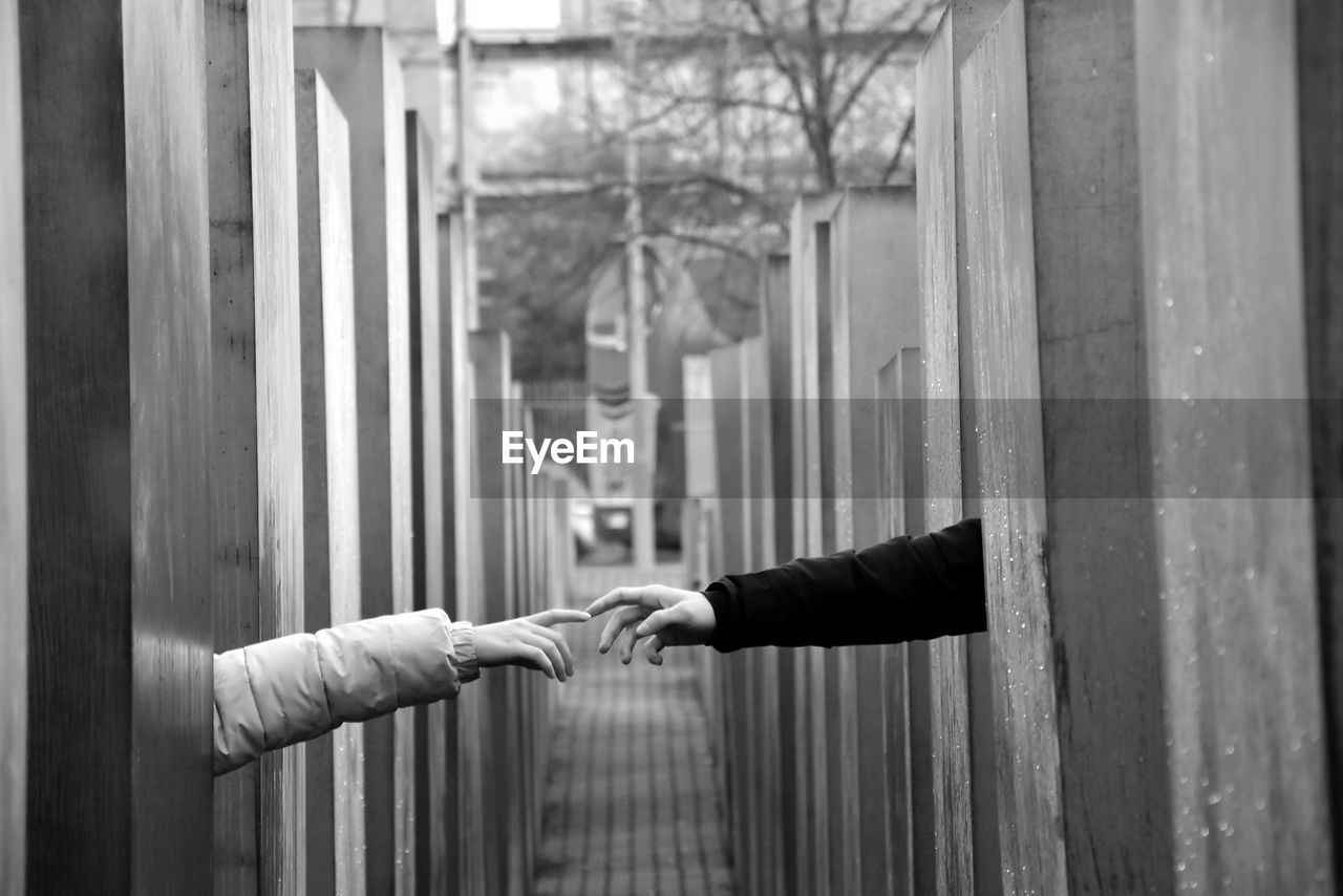 Cropped hands of couple by wooden columns