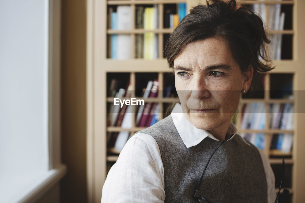 Close-up of thoughtful female lawyer against bookshelf in library