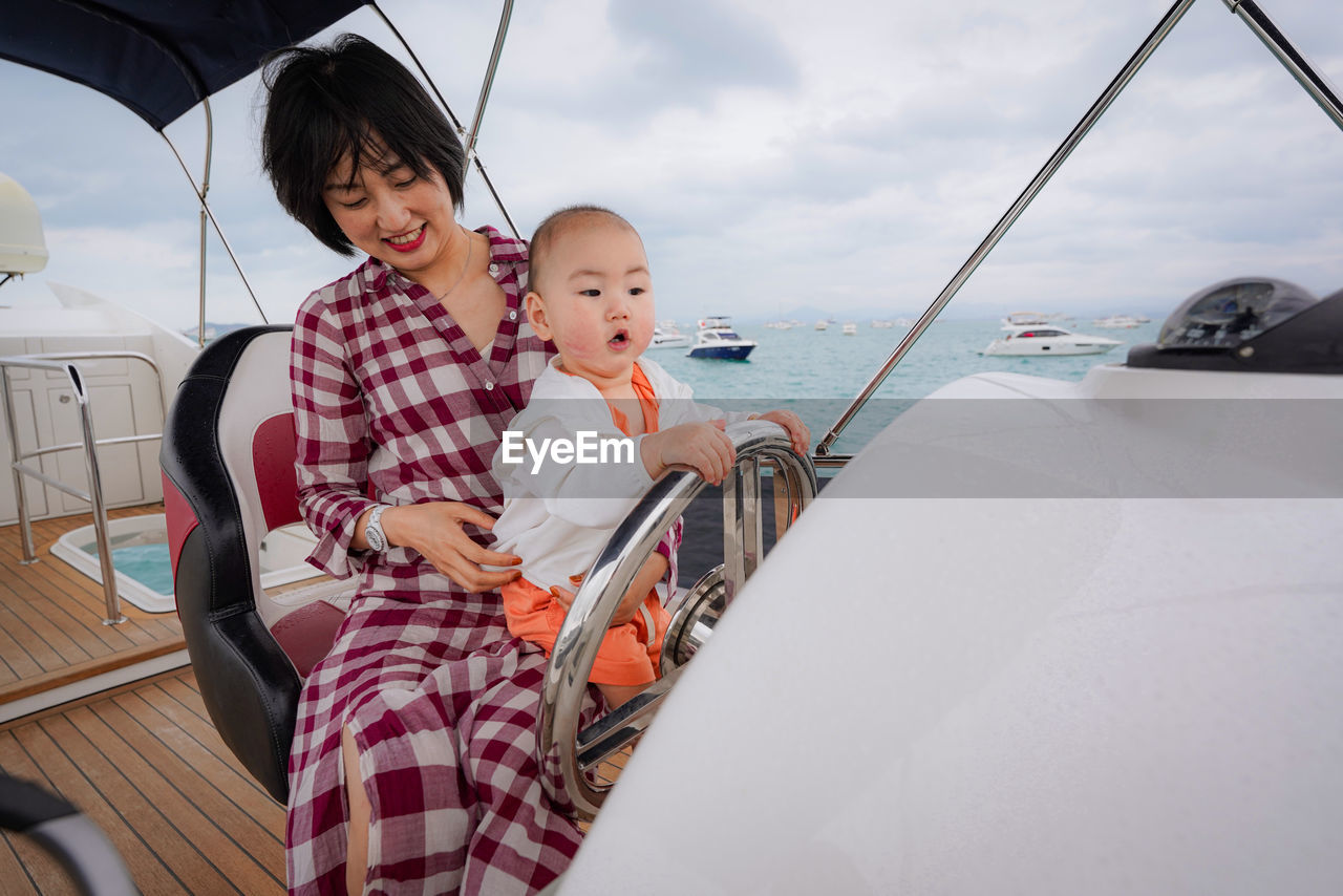 Cute boy holding steering wheel of yacht in sea