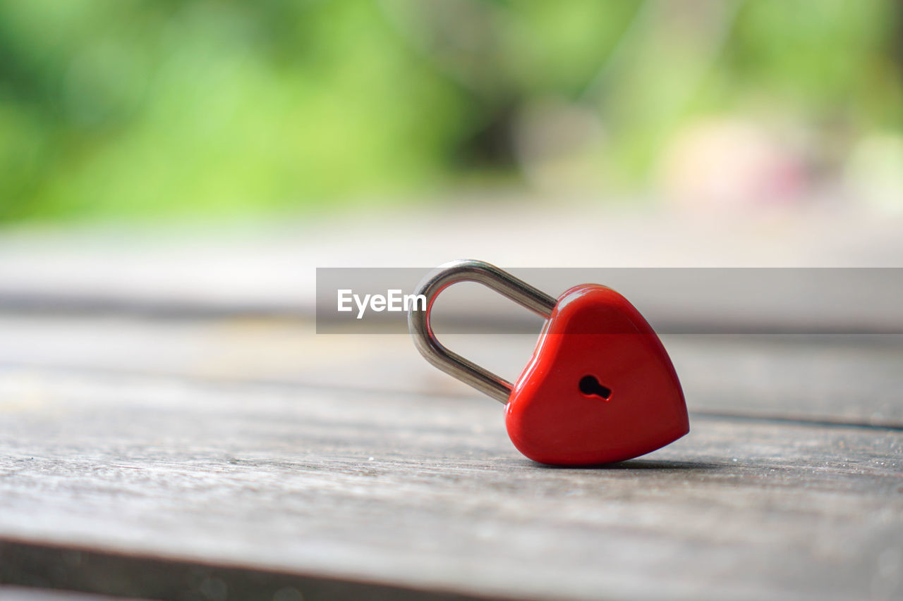 Close-up of red heart shaped padlock on table