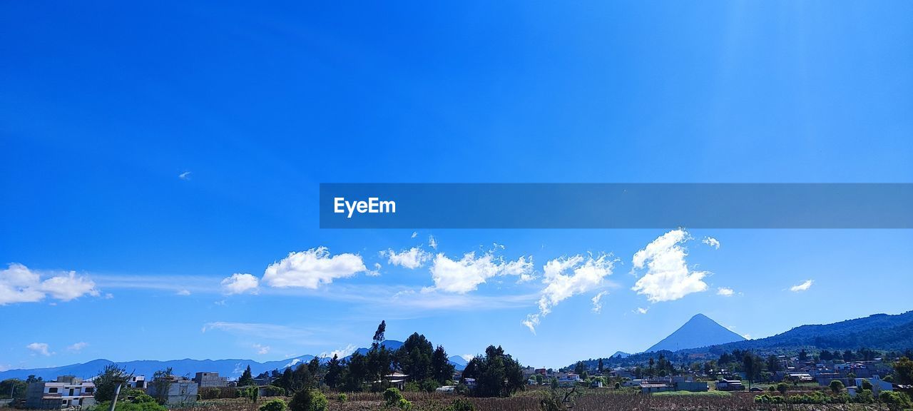 sky, blue, mountain, landscape, horizon, environment, architecture, scenics - nature, cloud, nature, mountain range, travel destinations, building, beauty in nature, travel, built structure, city, panoramic, building exterior, land, house, tourism, no people, outdoors, tranquility, dusk, tree, plant, religion, tranquil scene, village, rural scene, day