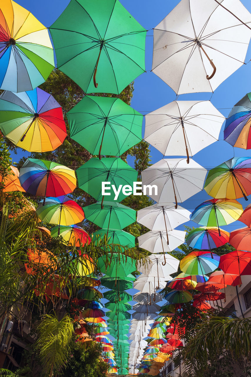 Low angle view of colorful umbrellas hanging against sky