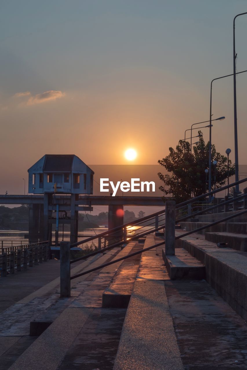 Street by sea against sky during sunset