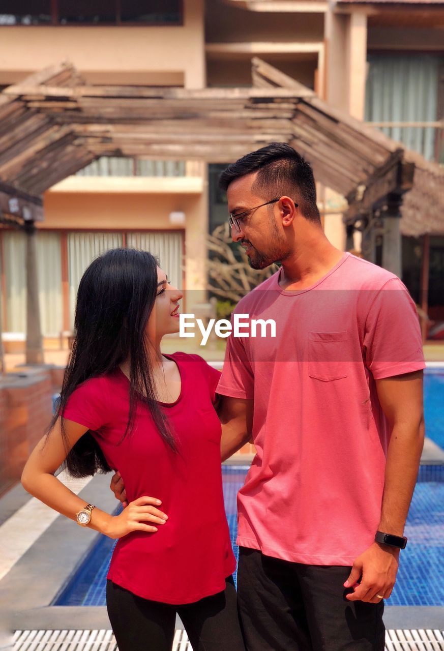 Young couple looking each other face to face while standing in tourist resort