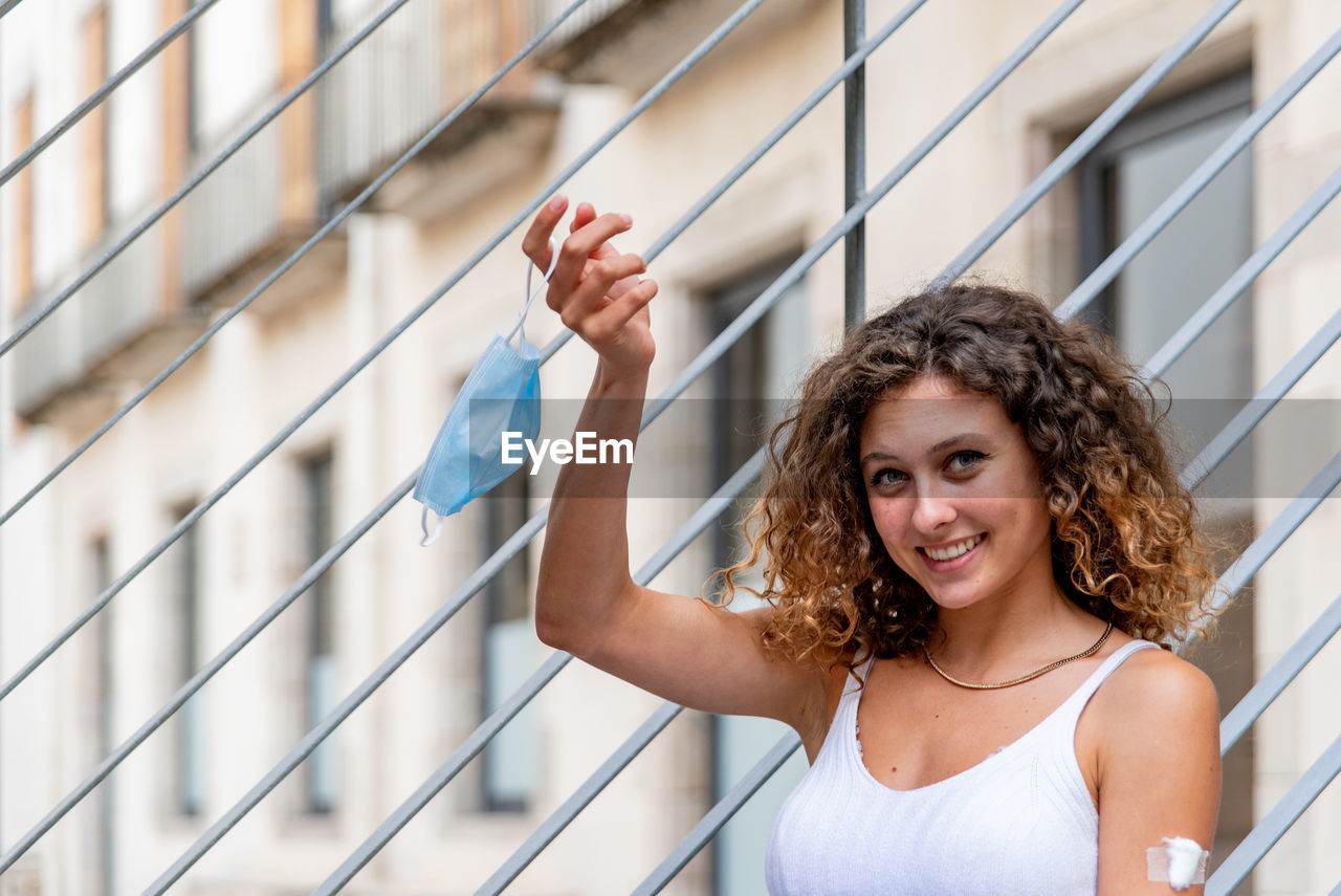 Young caucasian woman vaccinated taking off the mask