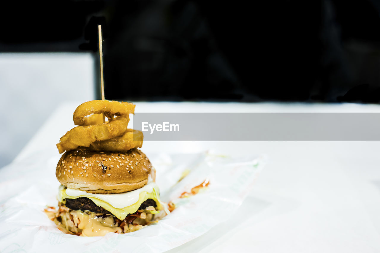 Close-up of hamburger with onion ring against black background