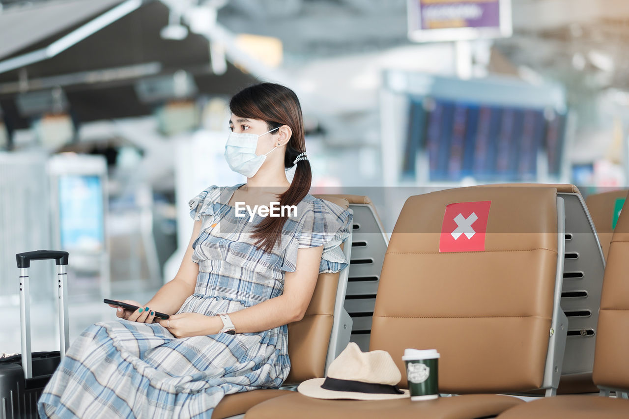 Woman wearing flu mask sitting at airport