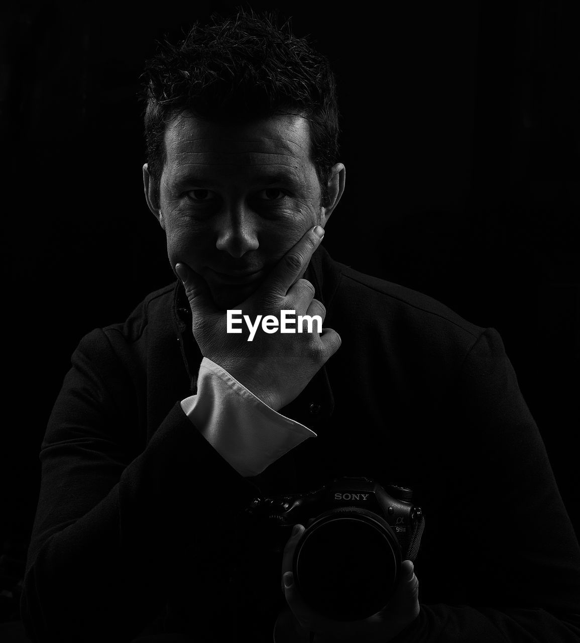 PORTRAIT OF YOUNG MAN HOLDING CAMERA