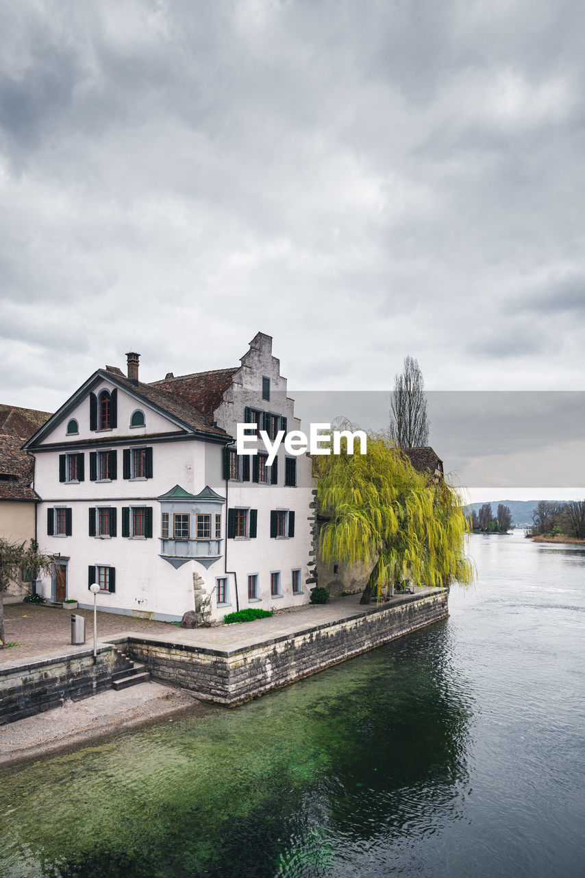 Buildings by river against sky