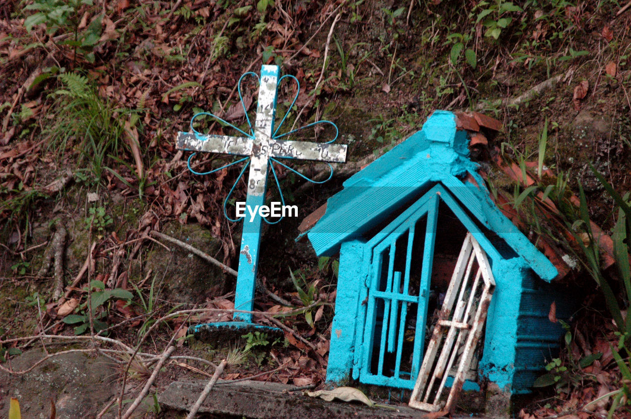 Cross by turquoise shrine on field