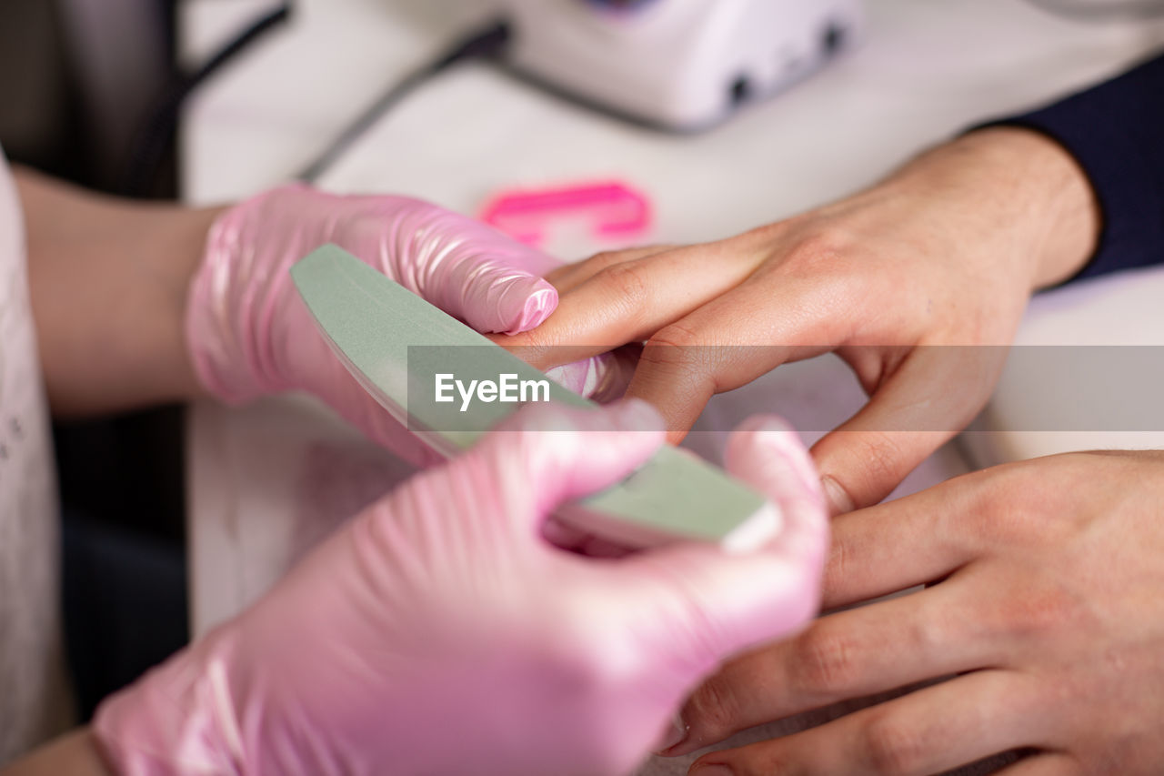 Cropped hand of beautician holding man hand